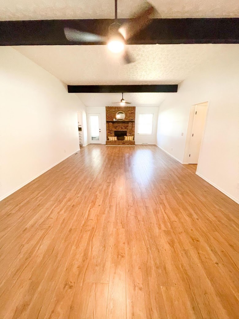 Vaulted living room with stained beams and brick fireplace — Ozark, MO